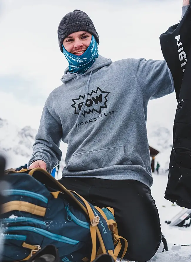 Professional snowboarder Adam Lambert smiling at the camera while holding snow gear.